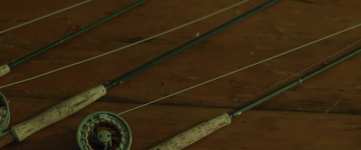 Man picks up one of three fishing poles sitting on a table next to each other