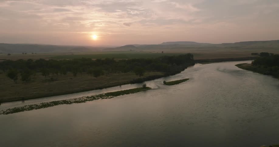 Aerial of a river in between a forest area at sunset