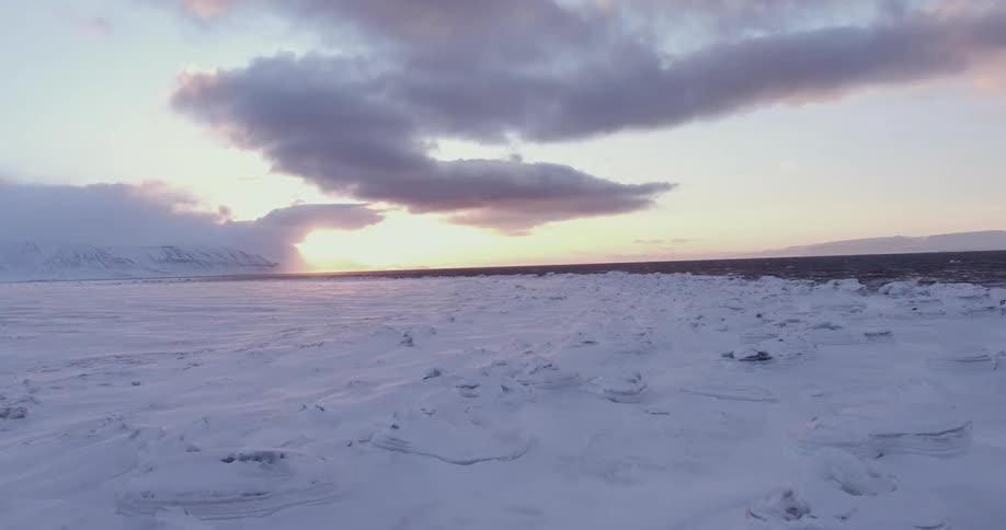 A man looks out to sea as he stands in a frozen landscape