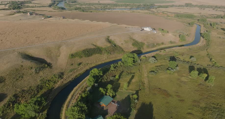 Aerial shot of a winding river in a wooded area with fields