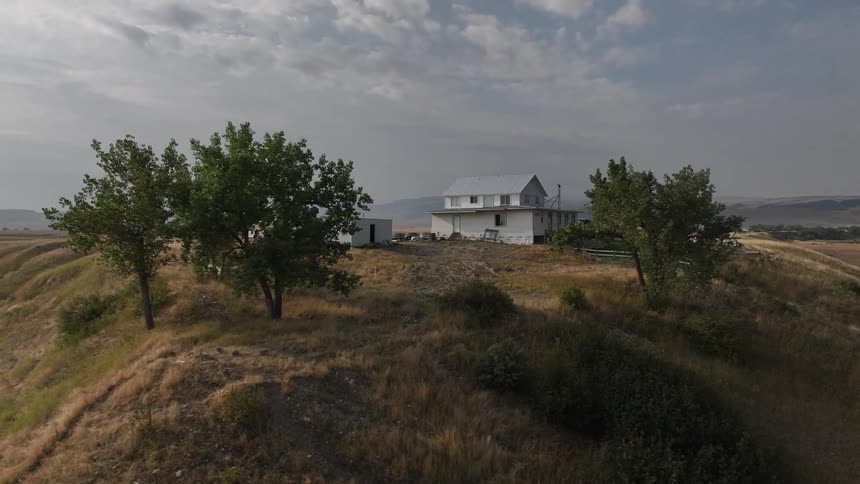 House with rural area built on a hill surrounded by mountains on the horizon