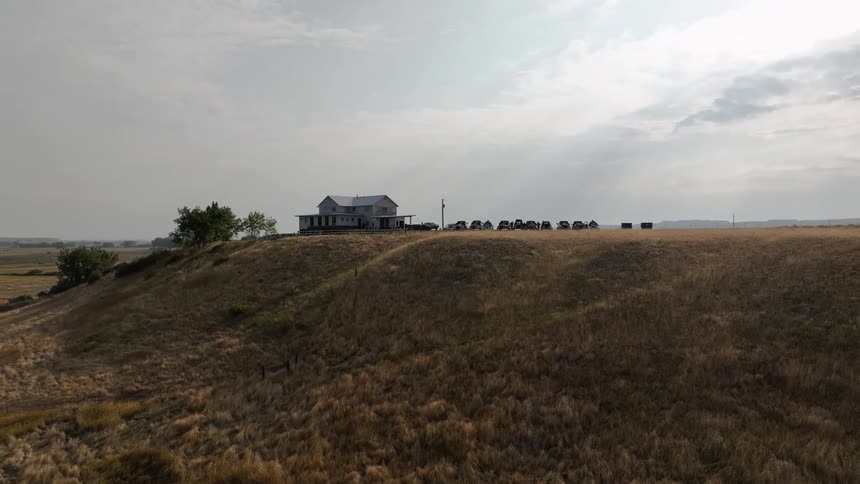 House on a hill surrounded by dry grass under a cloudy sky