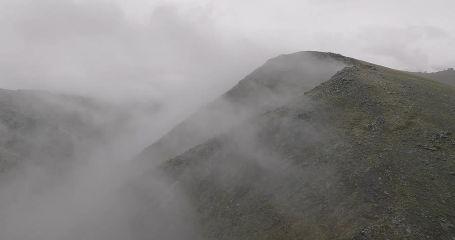 Fog touches mountaintops under a cloudy sky