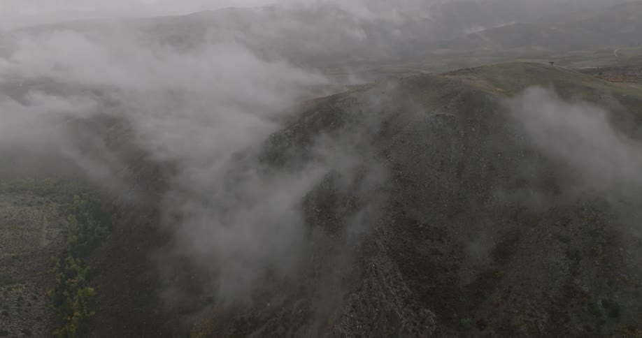 Low lying clouds hover over mountainous terrain on a foggy day