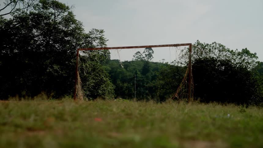 An old rusty goal post on an unkempt soccer field outdoors during daytime