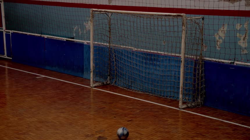 A ball rolls into a goalpost in an indoor soccer sports venue during daytime
