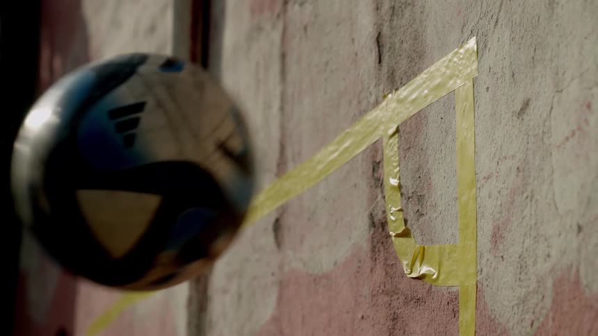 Close up of a soccer ball played against a wall outdoors during daytime