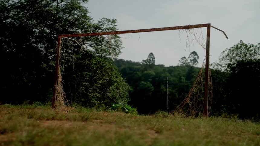 A dilapidated netted goalpost on a soccer field outdoors during daytime