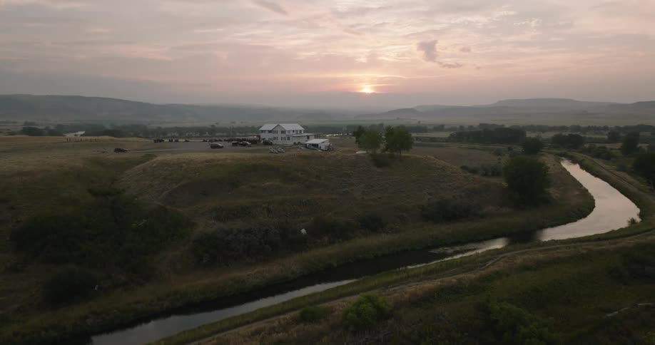 A vehicle is driving towards the rural home on a hill