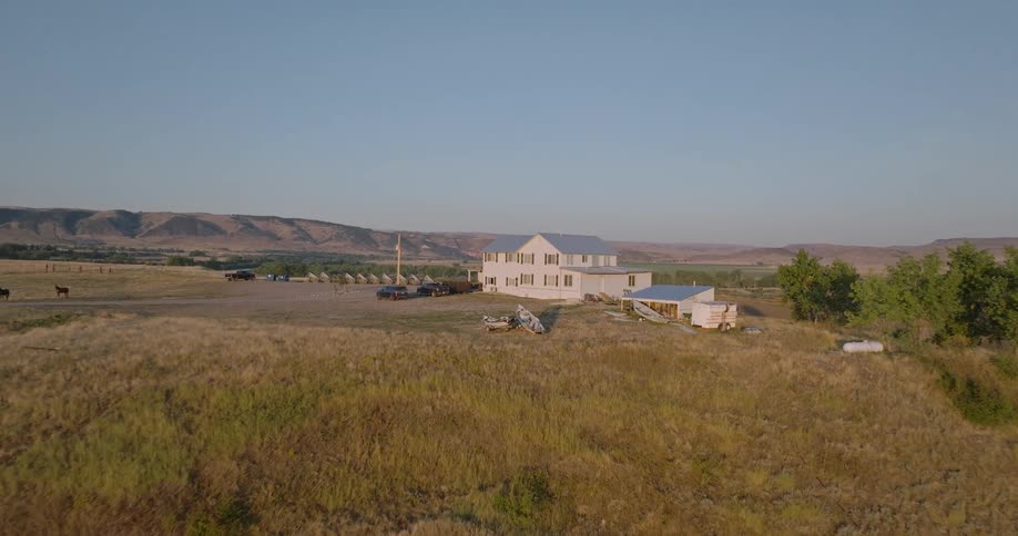 Aerial view of a large house on a hill surrounded by mountains