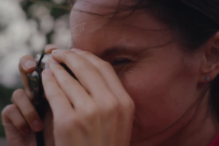 The face of a woman who is using a small camera to take pictures