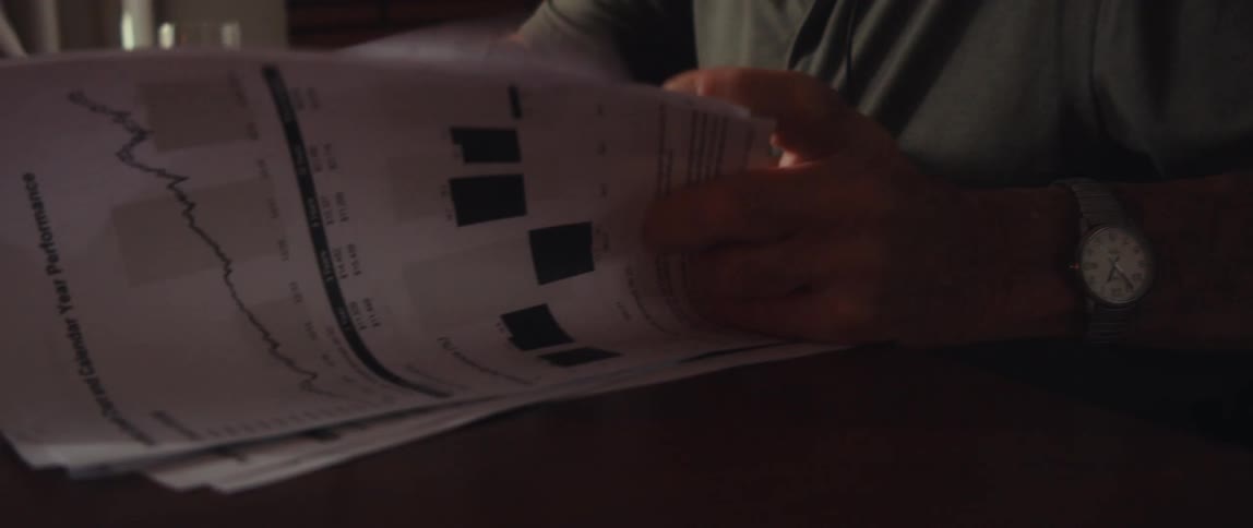 An elderly man sitting at a table thumbing through some papers
