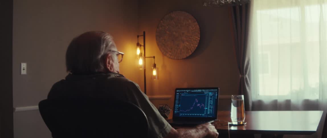 The man reacts to a line graph on his laptop