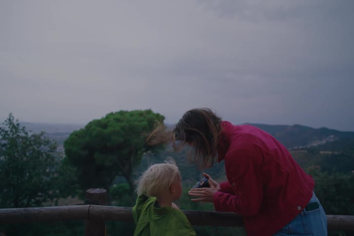 A woman shows her son a camera on the mountain top