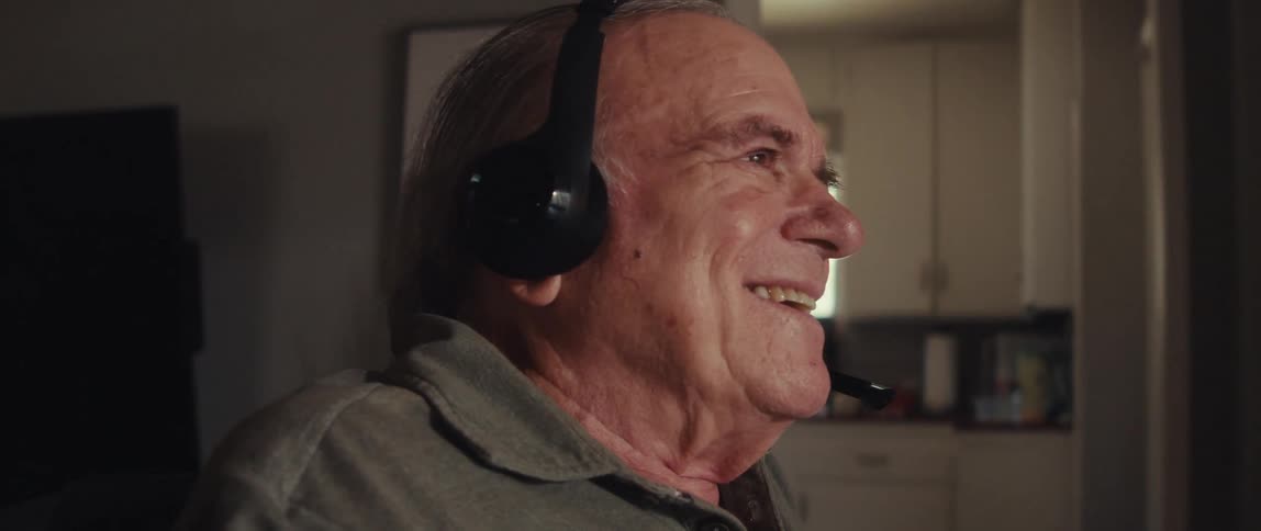 Man wearing a headset smiles while talking animatedly