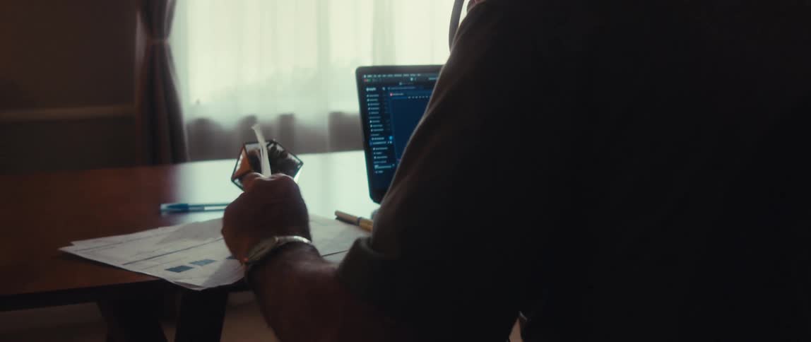 A man is writing in front of his computer
