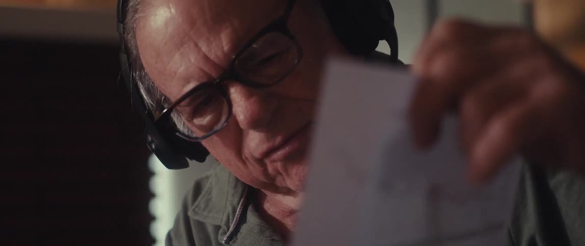 The man is thinking and talking while pointing at a paper