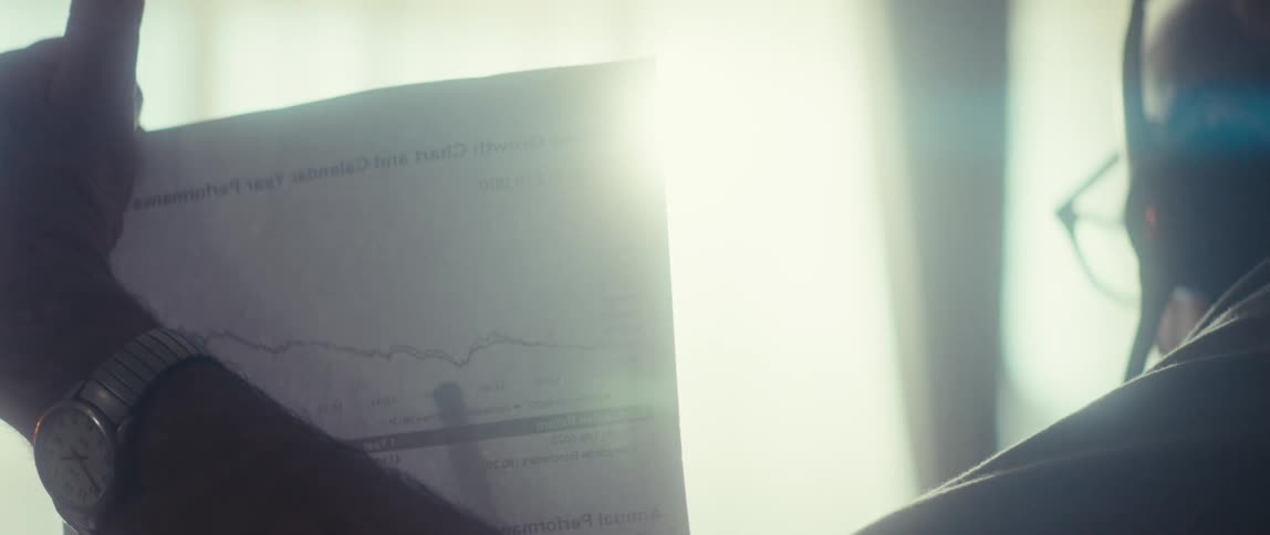 Older man points to the graph on the document he is holding while talking