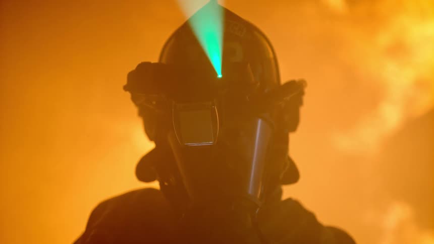 Firefighter slowly turns his head while wearing a helmet with an active laser