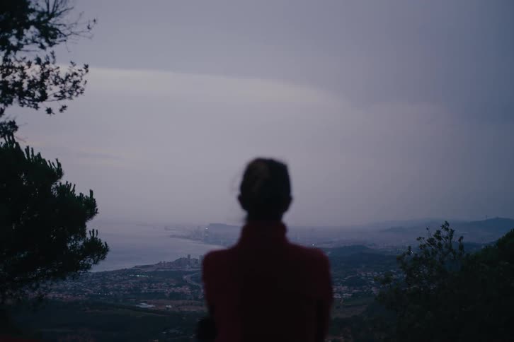 Woman from behind enjoying the view of a city and the sea in the background