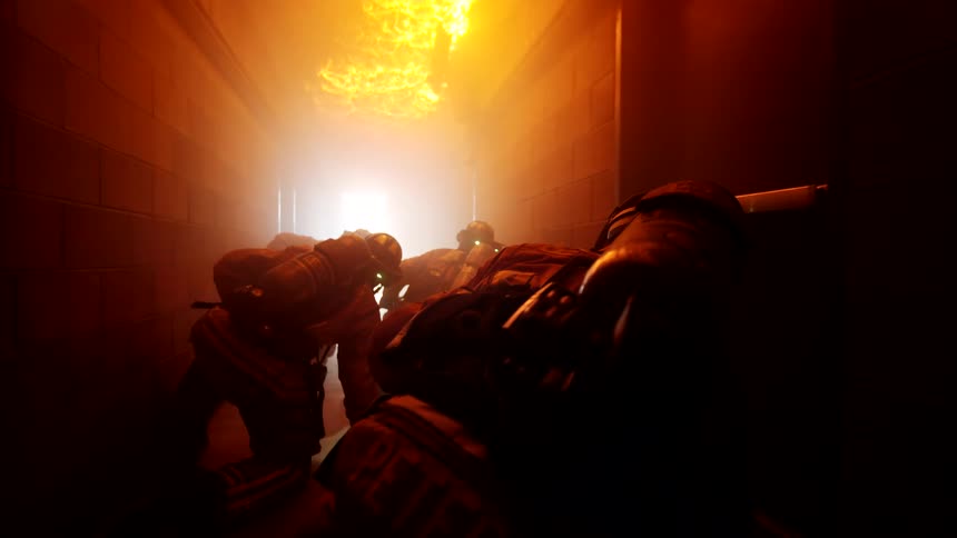The ceiling is on fire as the firefighters crawl under it