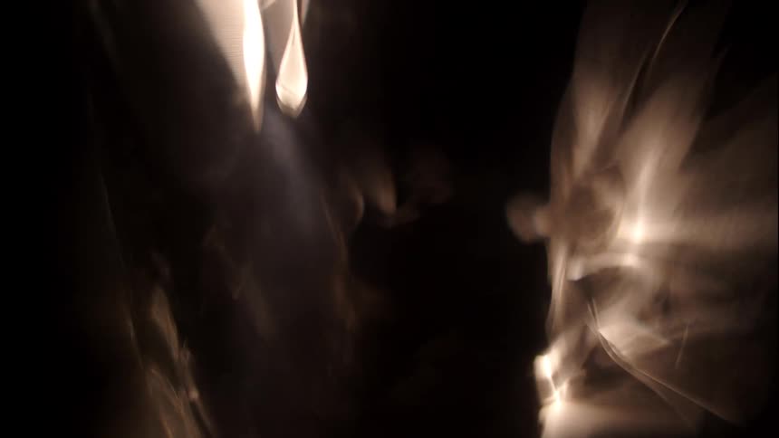 Glowing orbs and streaks of light scatter across a dark background creating layered reflections