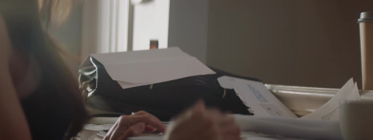 Woman throwing paperwork on top of a bag