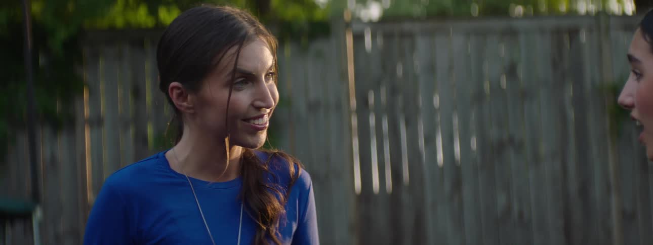 Close up of two female teenagers conversing while standing outdoors during daytime