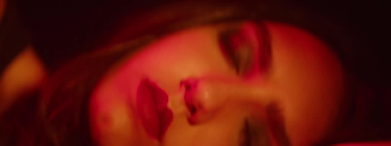 A young woman sleeps in a dark room illuminated by deep red light