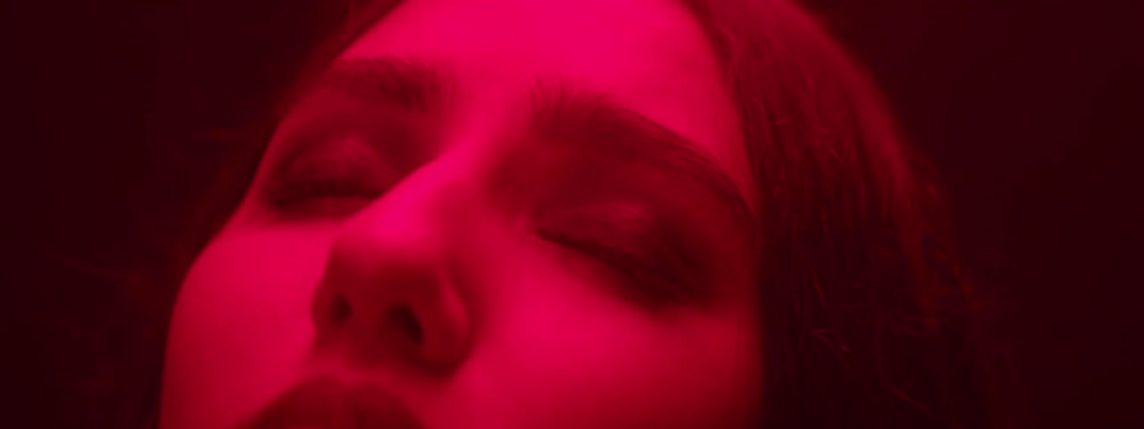 The red light is covering the girls face in the dark room