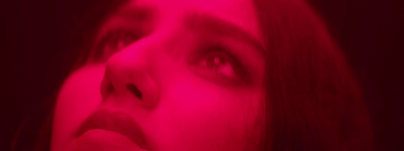 The girl looks up at the red light and blinks