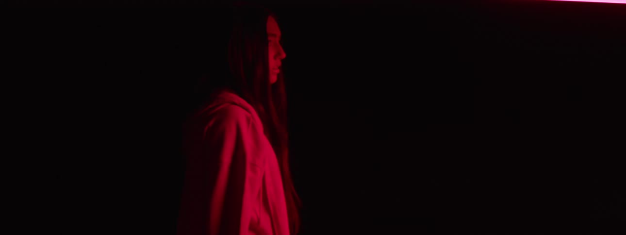 Young woman stands in a bedroom illuminated by red lighting