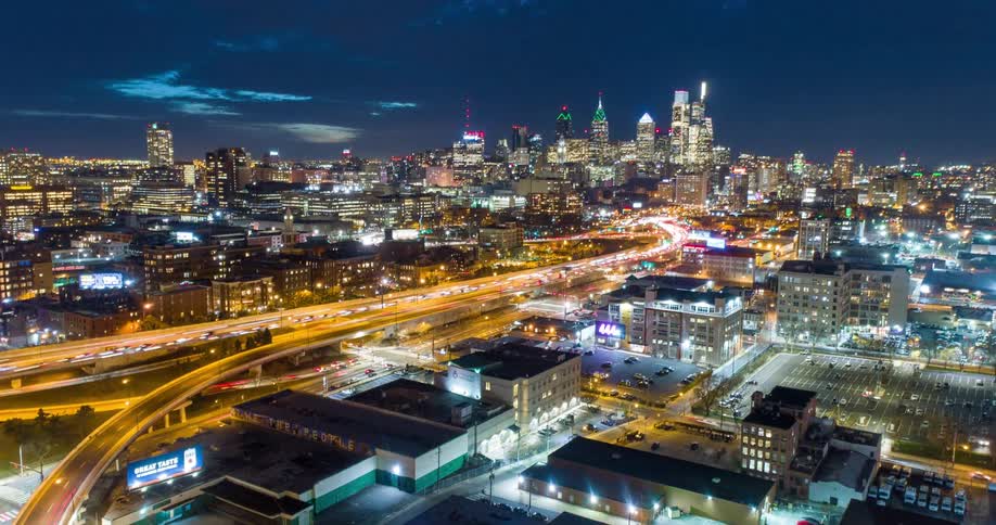 Traffic moves fast through a brightly lit Philadelphia at night