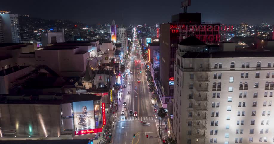 A high angle night view over Hollywood Blvd  with tall buildings including the brightly lit Roosevelt Hotel with vehicles moving along the road