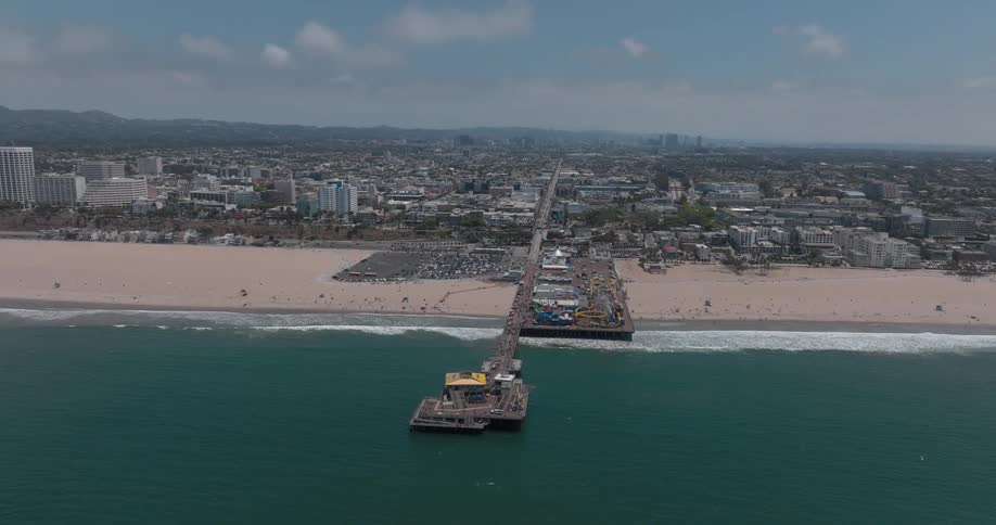 Santa monica pier beach with the city of santa monica in the background as ocean waves hit the shore at midday