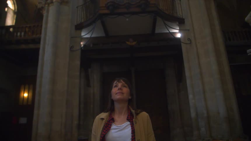 Woman walking inside a building is looking up and smiling