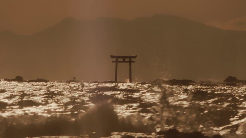 A wooden torii is in the rough ocean