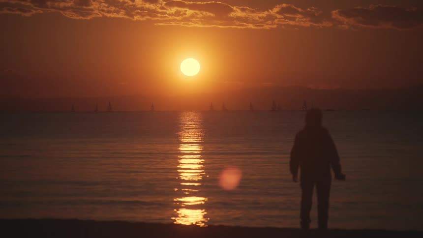A person watches the red sky as the sun rises