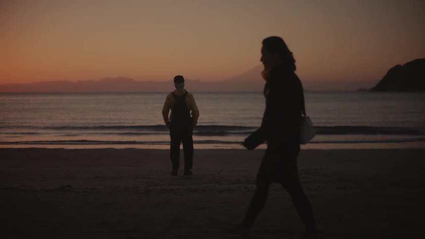 Two people are admiring the sunset at the sandy beach