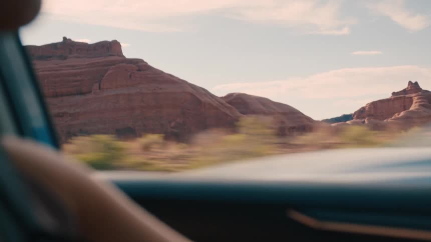 Landscape of mountains and canyons seen through the window of a car with a person driving