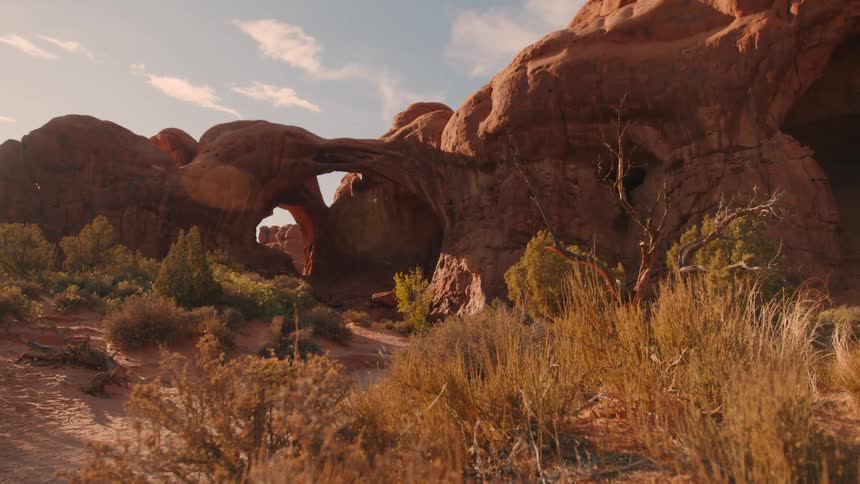 Red rock arches rise in a desert under a golden sky