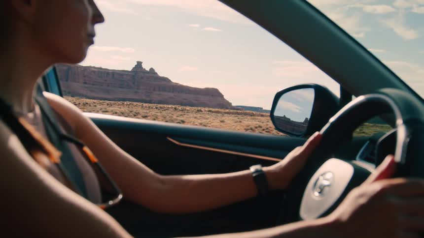 Woman is driving her vehicle through desert landscapes