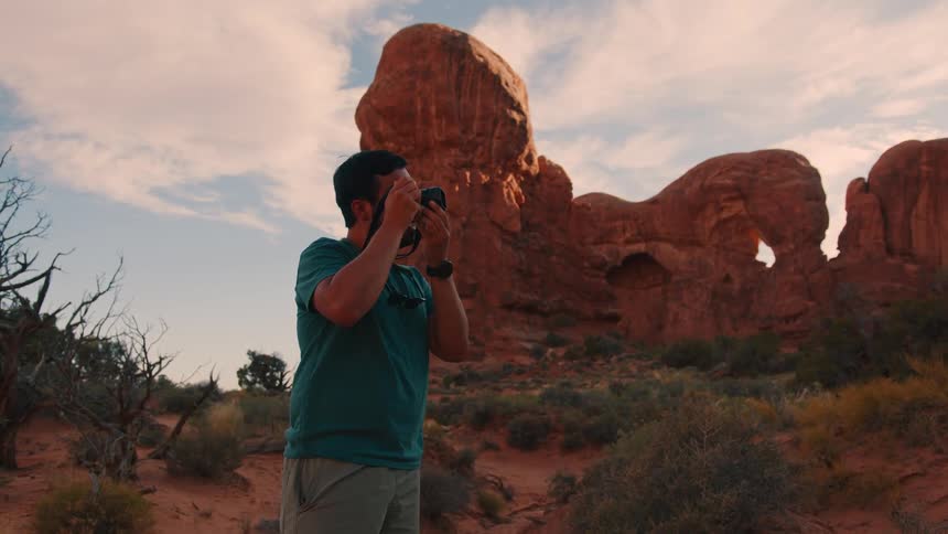 A man is in the mountains of a desert takig photographs