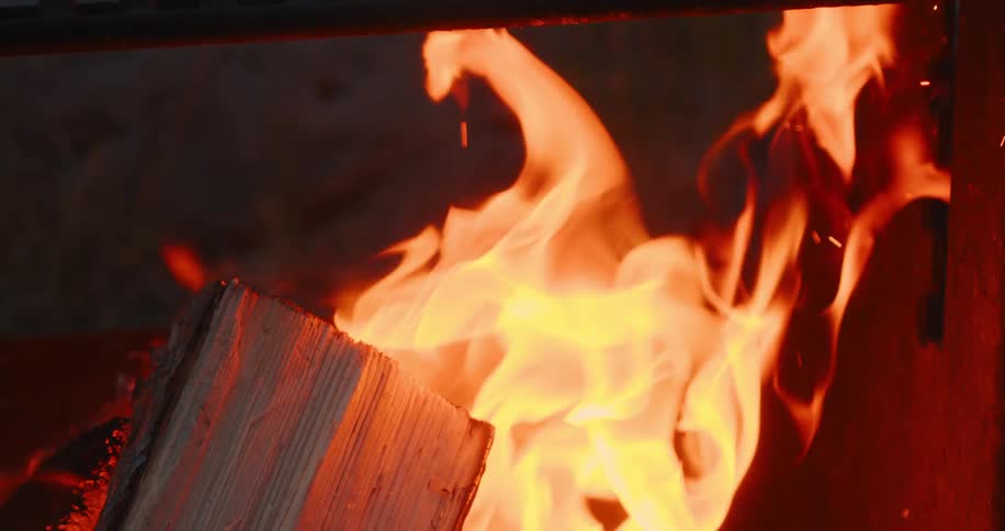 A bonfire with a piece of firewood burning with a glowing orange flame