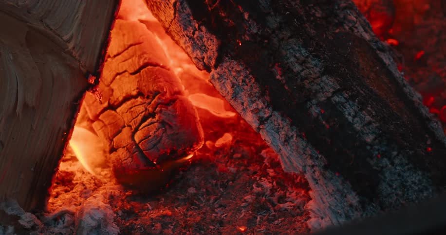 Very burnt logs on fire in a tepee formation
