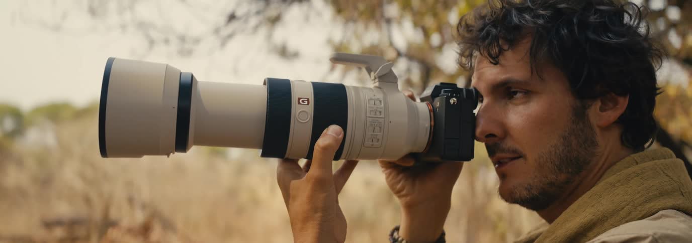 A man with a black and white camera in front of his face and it is pointed forward and then he puts the camera down
