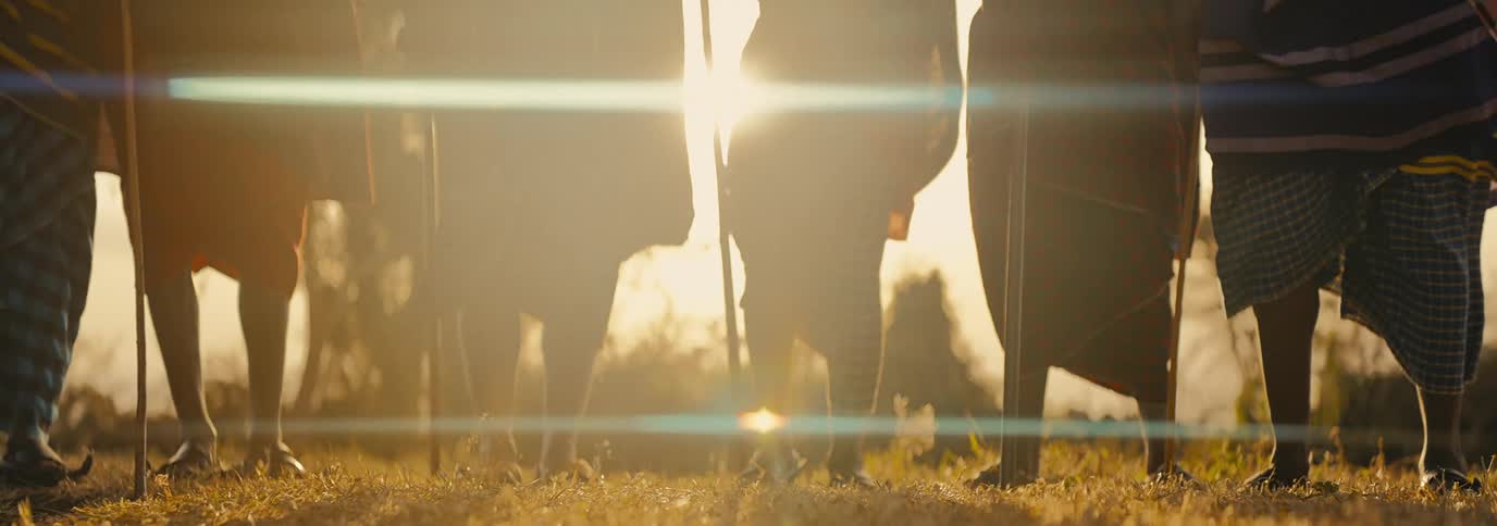 People of a tribe in a field with one of them jumping