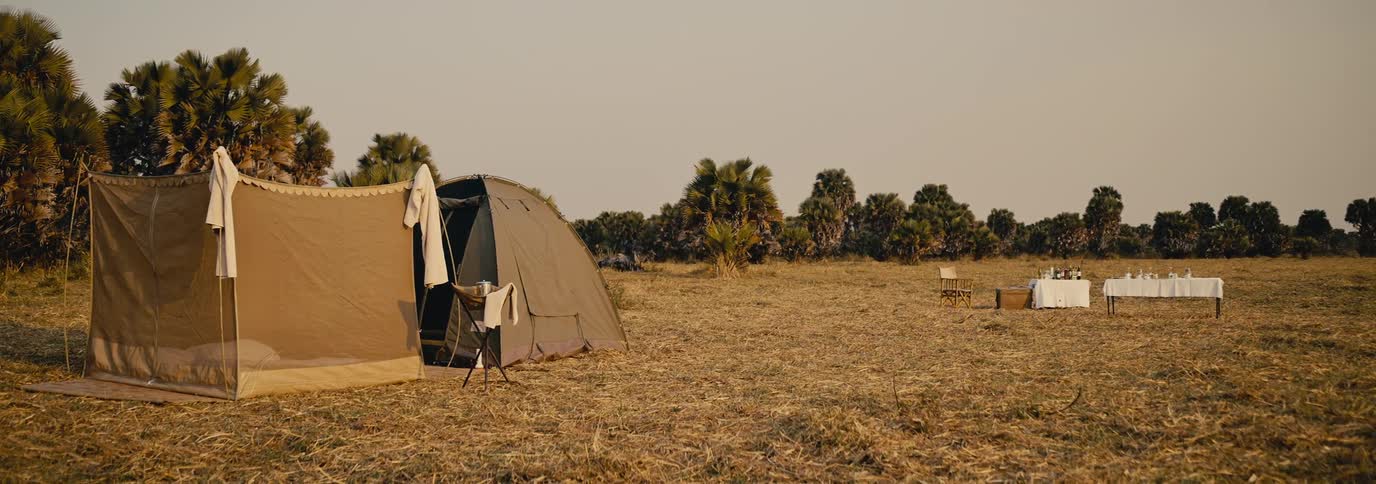 Tent in a natural field with a dining table arranged in the background