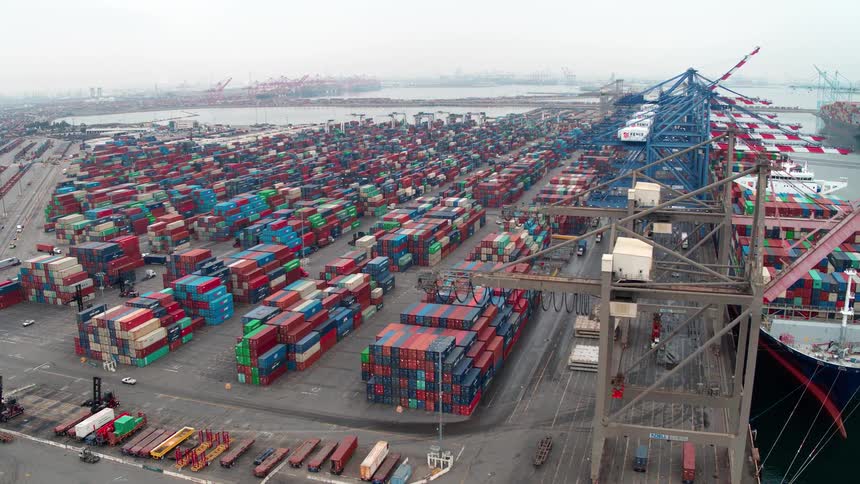 Aerial view of a busy shipping port filled with stacked cargo containers and large docked ships in Los Angeles