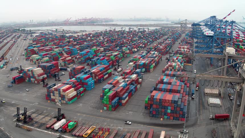 Aerial view of a busy  Los Angeles port with stacked cargo and cranes